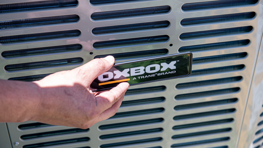 closeup of an AC tech hand placing logo label on new AC installation for residential home