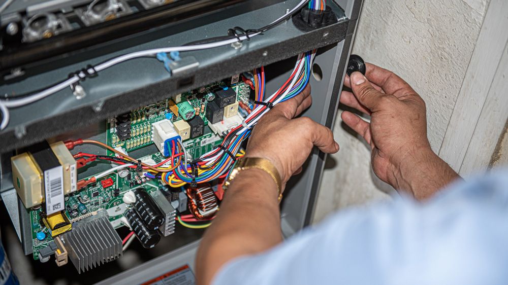 a closeup of a HVAC technician working on AC repairs and wiring for a residential AC unit