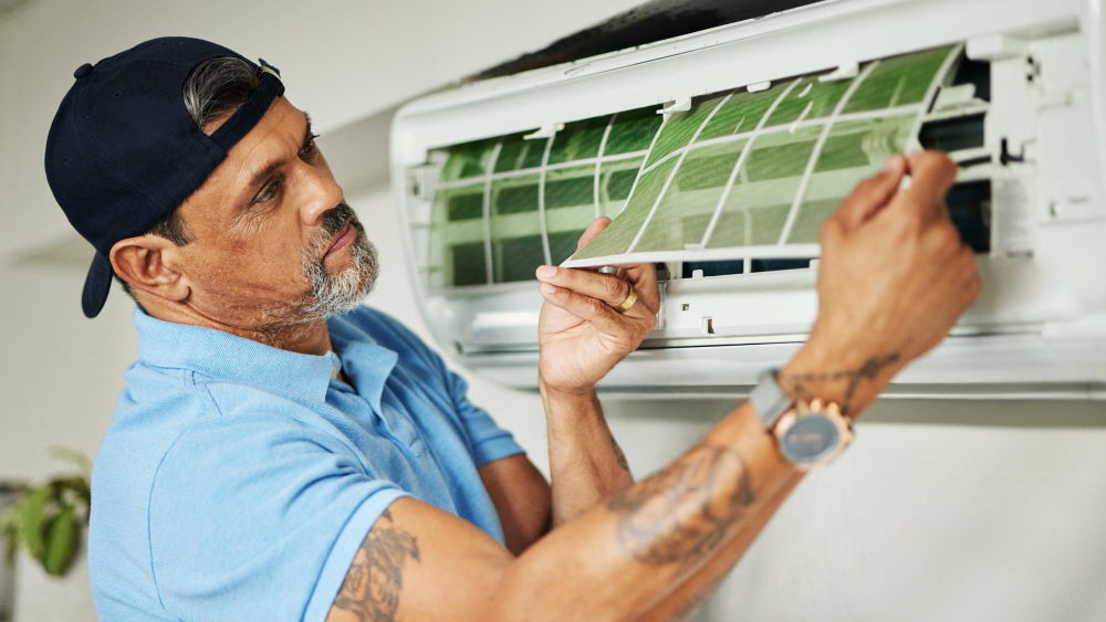 male HVAC technician cleans or replaces the filter in a wall-mounted air conditioner after teh $5000 rule of air conditioning