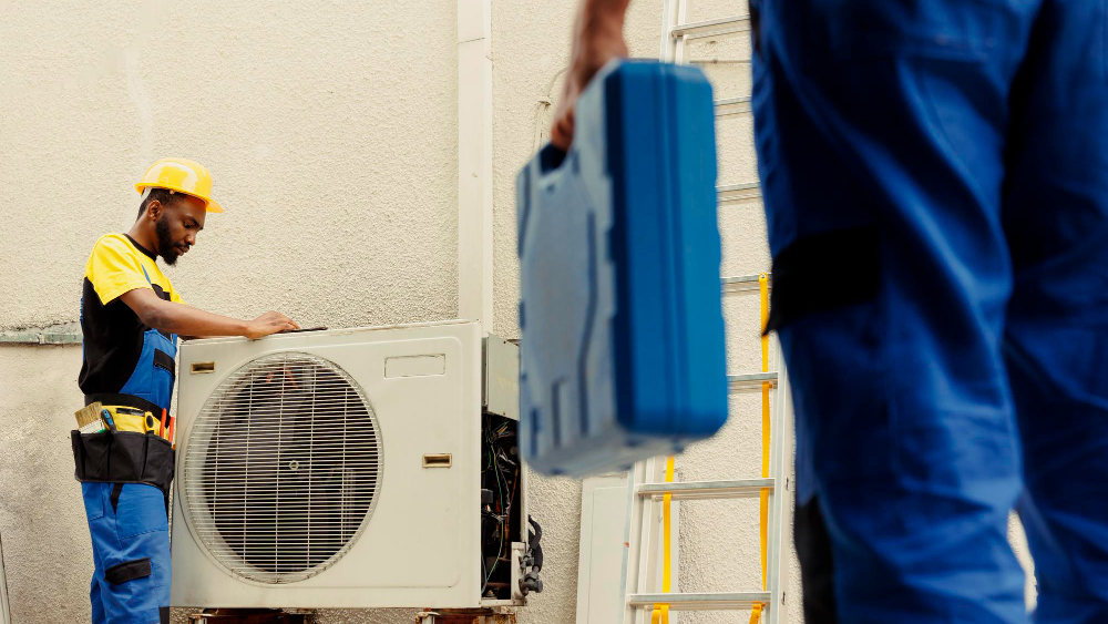 HVAC technicians servicing an outdoor AC unit, illustrating “how long do AC units last”.